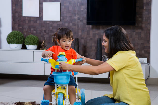 Mixed race woman teaching son to ride tricycle Mother, Son, Happiness, Love, Riding, indian boy barefoot stock pictures, royalty-free photos & images