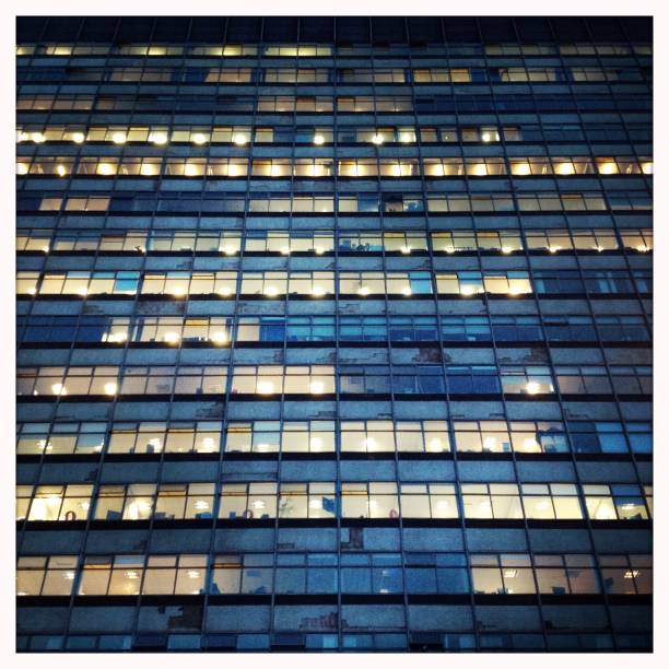 Facade of office building at dusk A London office building at night. Shot with a cellphone. großunternehmen stock pictures, royalty-free photos & images