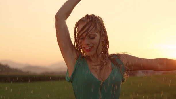 close-up: menina sorridente fica encharcada enquanto ela dança em uma noite linda. - wet dress rain clothing - fotografias e filmes do acervo