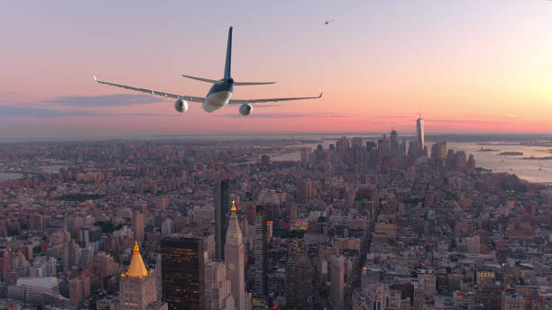 航空写真: 乗客の飛行機が夕日でマンハッタンのダウンタウン上空を飛行します。 - landing sunset airplane flying ストックフォトと画像