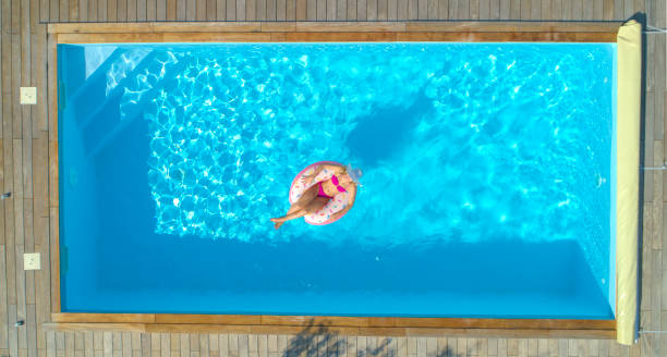 istock AERIAL, TOP DOWN: Cheerful woman sunbathing while relaxing in her backyard pool. 1051372992