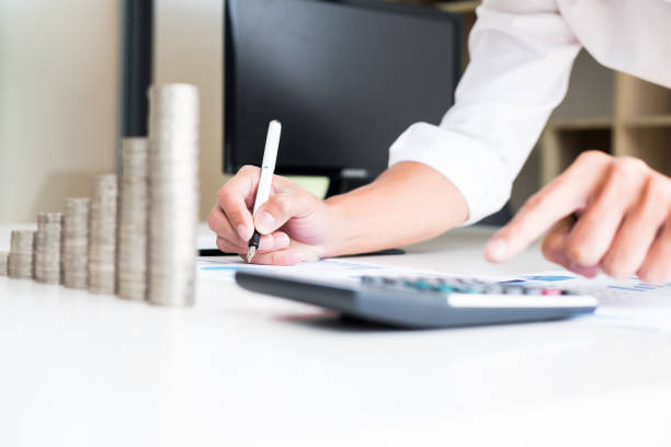 istock Cropped Image Of Businesswoman Using Calculator While Writing On Document 1051379968