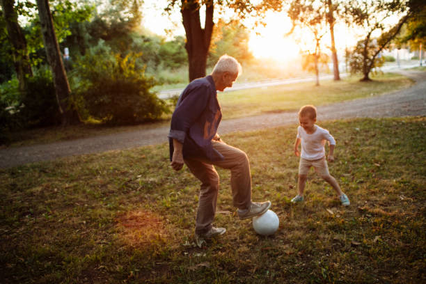 Soccer game with grandpa Kid and grandpa playing a soccer game outside on a beautiful sunny day old football stock pictures, royalty-free photos & images