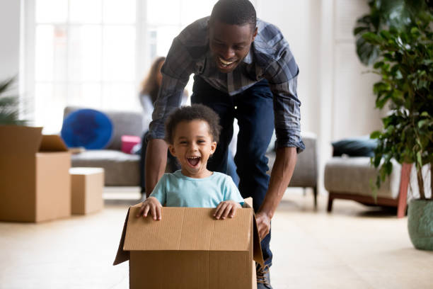 istock Black father and son playing with box at home 1051381370