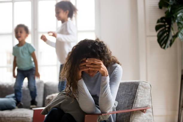madre triste y en casa los niños juguetones - madre desesperada fotografías e imágenes de stock