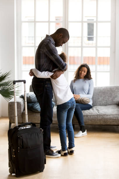 Unhappy black father leaving family daughter crying at home Married couple and little daughter in living room at home. Sad unhappy father hugs small daughter. Parents divorcing, break up, child stay with mommy dad leave with suitcase. Discord in family concept arguing couple divorce family stock pictures, royalty-free photos & images