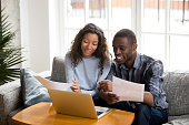 Positive black couple with bills and laptop at home