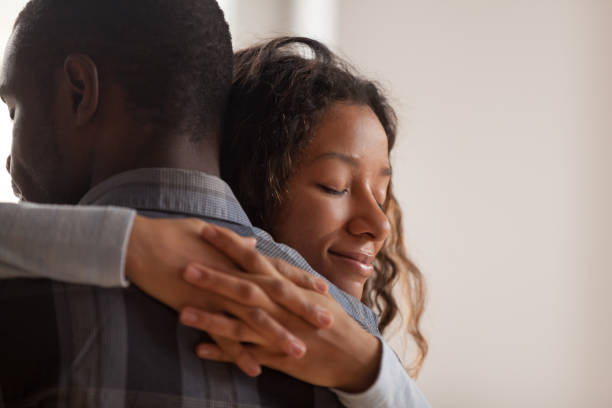 Close up black African wife embracing husband Close up young black american wife embracing husband. Portrait of woman with closed eyes, man rear view. Attractive affectionate couple in love, romantic relationship support and gratefulness concept happy woman sad man stock pictures, royalty-free photos & images