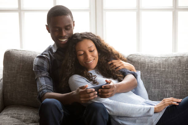 istock Black couple in love on couch using mobile phone 1051381602