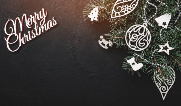 istock Horizontal top view. With space for your text. Effect of lights. Christmas greeting card on black stone background with a green fir tree with wooden toys 1051394806