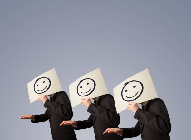 istock Men in suit gesturing with sketched smiley faces on cardboard 1051398388