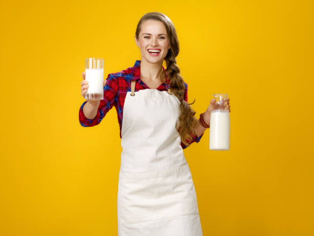 uśmiechnięta kobieta gotować dając szklankę domowego świeżego surowego mleka - mleczarz zdjęcia i obrazy z banku zdjęć