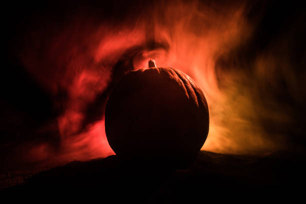 Halloween theme with pumpkin against smoky dark background. Empty space for text