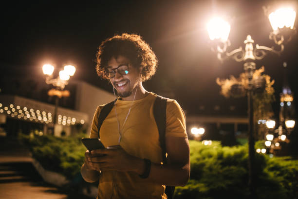modern black student texting on his mobile phone and smiling at night - night school imagens e fotografias de stock