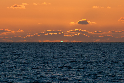 A natural phenomenon, the setting sun casts a green light as it dips below the horizon.