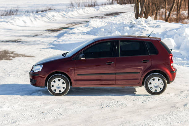 volkswagen polo kastanienbrauner farbe auf der winter-straße, nicht-städtisches - winter non urban scene snow tree stock-fotos und bilder