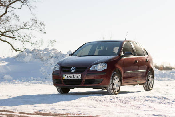 volkswagen polo kastanienbrauner farbe auf der winter-straße, nicht-städtisches - winter non urban scene snow tree stock-fotos und bilder