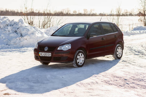 volkswagen polo kastanienbrauner farbe auf der winter-straße, nicht-städtisches - winter non urban scene snow tree stock-fotos und bilder