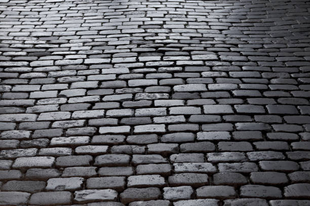 istock Cobbled stone road, reflection of light seen on the road 1051420826