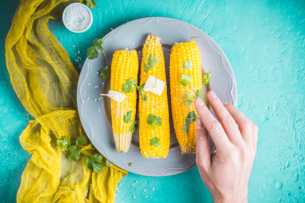 istock Boiled corn with butter and parsley on turquoise background. 1051421088
