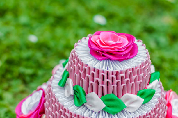 Pink birthday cake with 3D origami on green grass