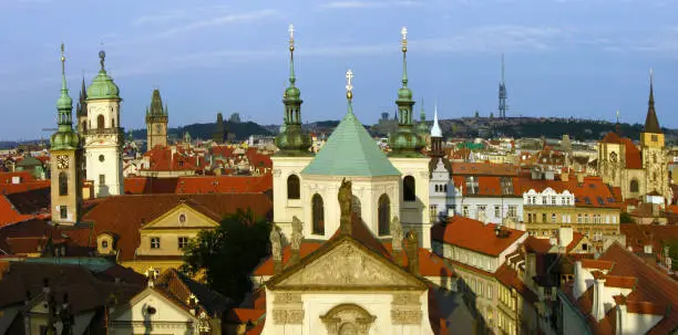 Shot from a high-up point of view, the amazing rooftops and church domes and towers of Prague. Panoramic, day time, sunny.