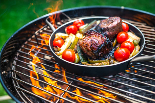 Preparing Meat With Vegetables in Frying Pan on Barbecue Grill.