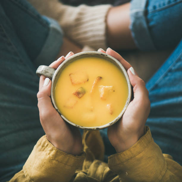 kobieta utrzymanie kubek z dyni żółty krem zupa, kwadratowe uprawy - spoon heat pumpkin eating zdjęcia i obrazy z banku zdjęć