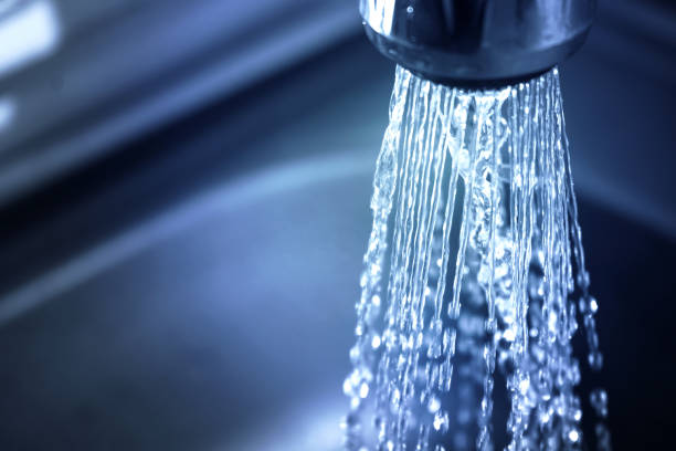 Concept water saving at home, reducing use. Water supply problems. Water tap with flowing water with spray. Selective focus