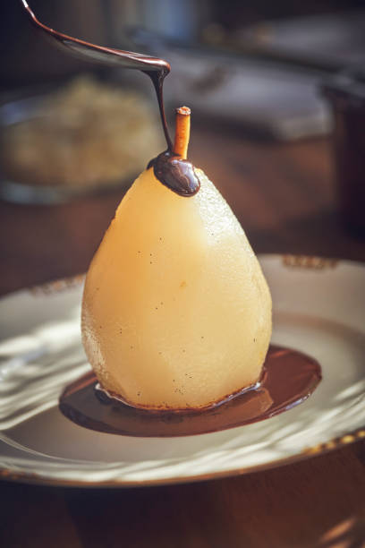 istock Preparing Poached Pears in Vanilla Lemon Syrup glazed with Dark Chocolate 1051443176