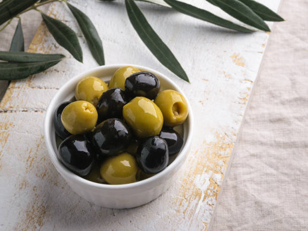istock Fresh olives mix, with rustic white wooden table on gray stone background 1051446548
