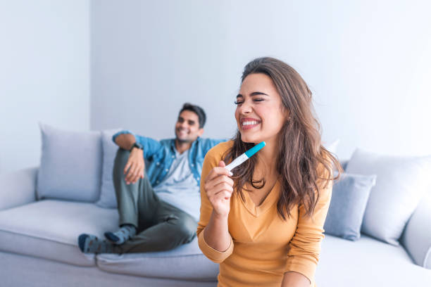 istock Attractive woman surprised and overjoyed reading pregnancy test 1051446676