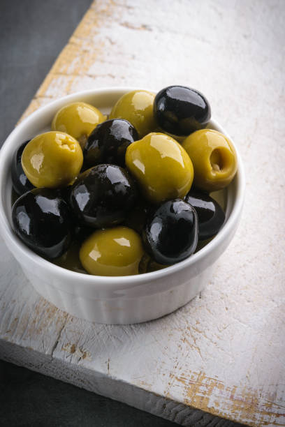 istock Fresh olives mix, with rustic white wooden table on gray stone background 1051446758