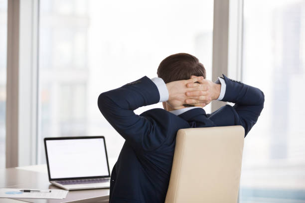 istock Businessman stretching in chair working at laptop 1051453282