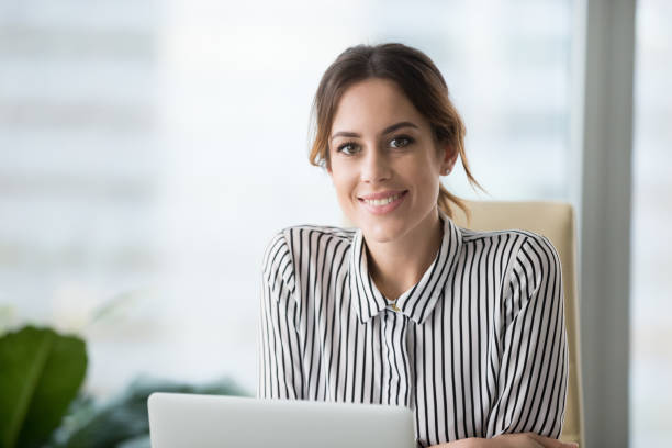 Portrait of smiling confident female boss looking at camera Portrait of smiling beautiful millennial businesswoman or CEO looking at camera, happy female boss posing making headshot picture for company photoshoot, confident successful woman at work assistant photos stock pictures, royalty-free photos & images