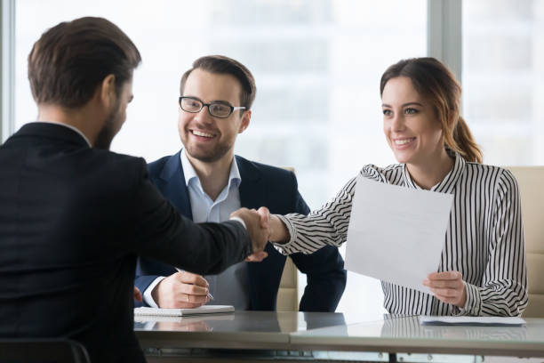 Smiling employers handshaking male candidate congratulating with hiring Happy employers shake hand of male job candidate, congratulating with given position, satisfied HR managers happy to hire applicant handshake greeting at team. Successful good interview concept recruiter stock pictures, royalty-free photos & images