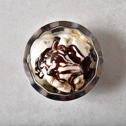 Overhead view of a bowl of butter pecan ice cream with chocolate syrup