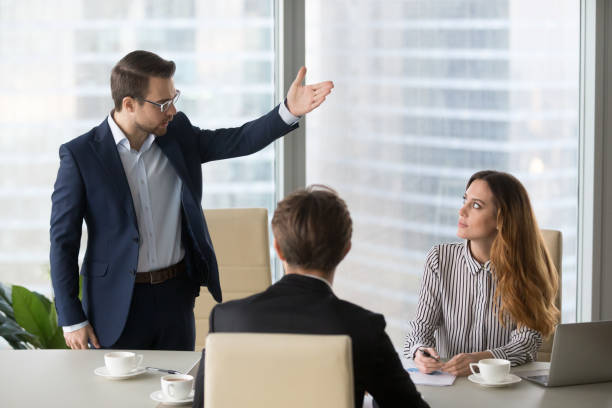 Mad male worker asking female partner leave meeting Mad male worker gesturing asking female colleague leave business meeting, angry businessman standing showing to doors having dispute with woman partner, associates argue at negotiations scolding stock pictures, royalty-free photos & images