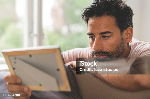 istock Man looking at old pictures while moving into a new house 1051454200