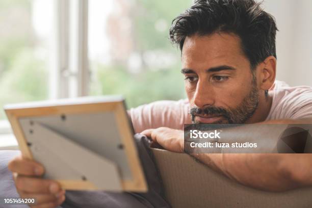 Man Looking At Old Pictures While Moving Into A New House Stock Photo - Download Image Now