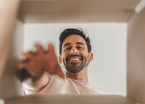 A mature hispanic man is packing and unpacking as he is moving into a new house.