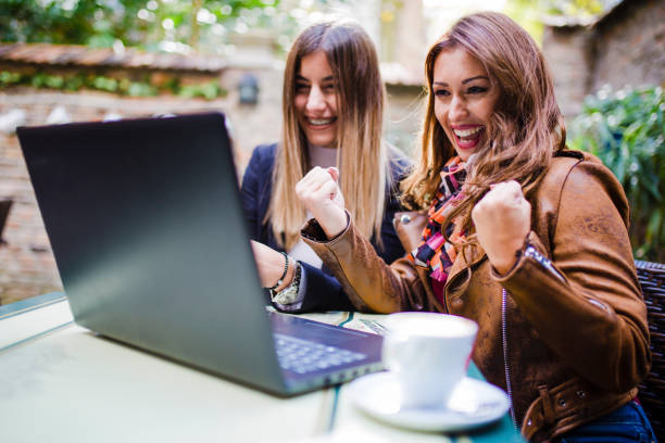 istock Two happy women online shopping at cafeteria 1051459650