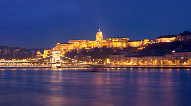Royal Palace of Buda night view Budapest, Hungary - March 06, 2016: Panorama of Royal hill featuring Illuminated Royal Palace and Chain bridge across Danube river danube river stock pictures, royalty-free photos & images