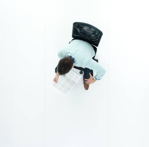 Directly above view of man wearing sweater and jeans, sitting down and reading document Directly above view of man wearing sweater and jeans sitting chair men stool stock pictures, royalty-free photos & images