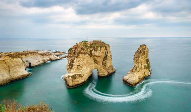 Rocks in sea near Beirut Rouche rocks in Beirut, Lebanon near sea and during sunset. Cloudy day in Beirut Lebanon at Pigeon Rocks in Mediterranean sea. lebanon beirut stock pictures, royalty-free photos & images