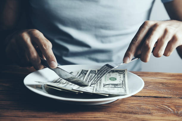 istock Hands cut money on plate reduce funds concept 1051499244
