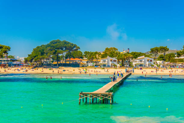 PORT D'ALCUDIA, SPAIN, MAY 24, 2017: People are enjoying a sunny day at Alcudia beach, Mallorca, Spain PORT D'ALCUDIA, SPAIN, MAY 24, 2017: People are enjoying a sunny day at Alcudia beach, Mallorca, Spain bay of alcudia stock pictures, royalty-free photos & images