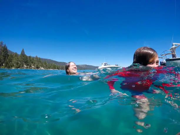 A family camps and enjoys the beauty of Emerald Bay in Lake Tahoe, California while paddle boarding, sailing, and swimming