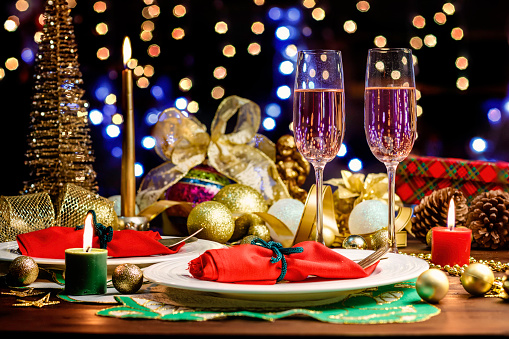 shot of Champagne flutes in table for two over golden holiday background. Christmas and New Year celebration