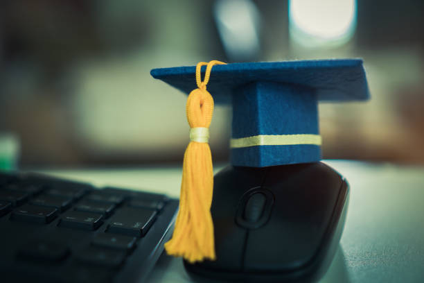 istock Graduate or Education knowledge learning study abroad international teachnology concept : Blue Graduation cap on mouse computer desk while student learn e-learning distant by internet enhance study 1051554860